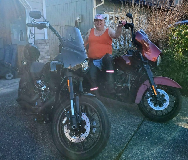 Darcy posing with two motorcycles.